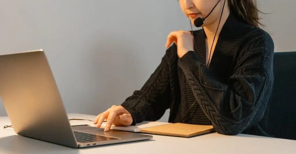 Asian woman in headset working on a laptop. Ideal for customer support themes.